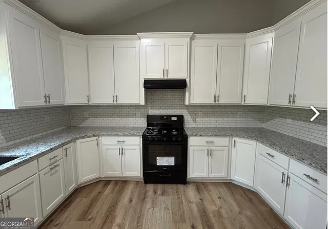 a kitchen with granite countertop white cabinets and stainless steel appliances