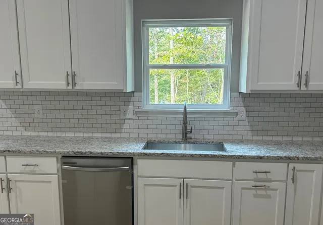a kitchen with granite countertop white cabinets and a window