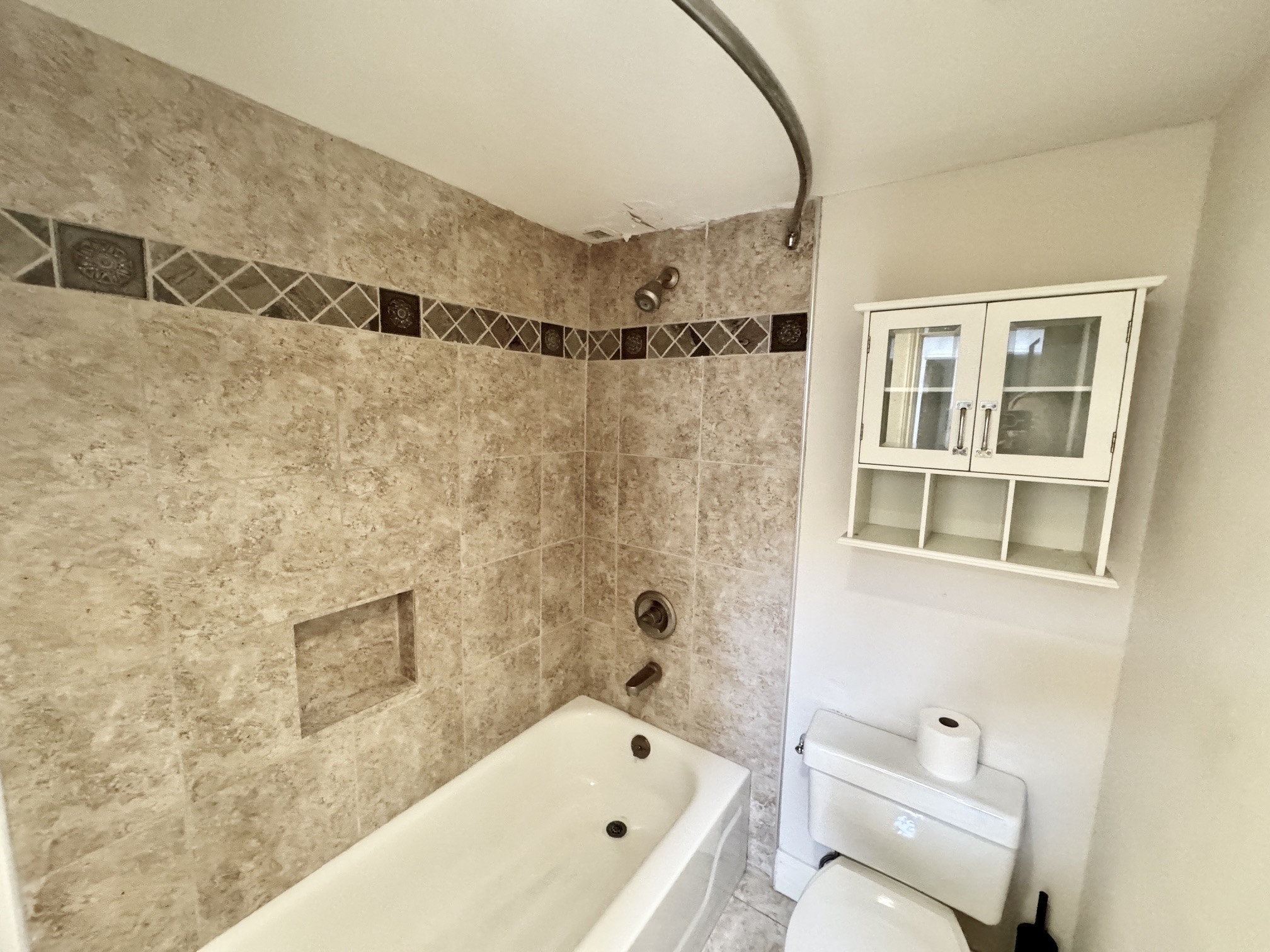 3525 Sage Road, Unit 404 Houston, TX 77056 - Photo 18 of 42 Hall bathtub/shower combination with custom tile surround and storage cabinet above the toilet