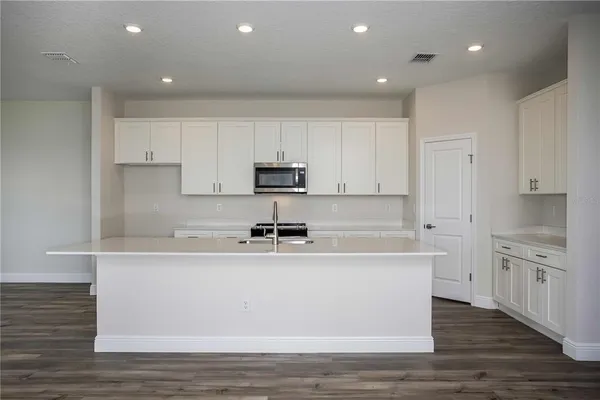 a kitchen with stainless steel appliances granite countertop a sink a stove a refrigerator and white cabinets