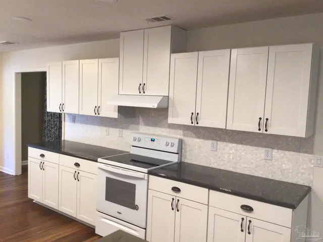 a large kitchen with stainless steel appliances wooden floors and view living room