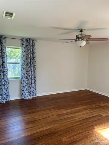 a view of an empty room with a window and wooden floor