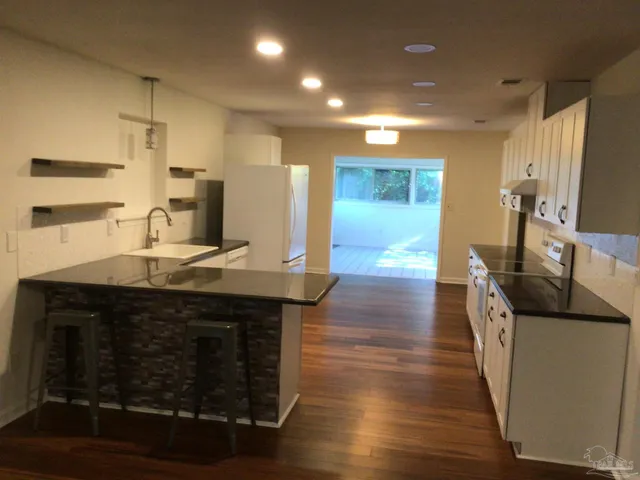 a kitchen with a sink a refrigerator and white cabinets