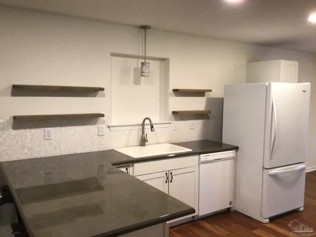 a kitchen with granite countertop white cabinets and white appliances