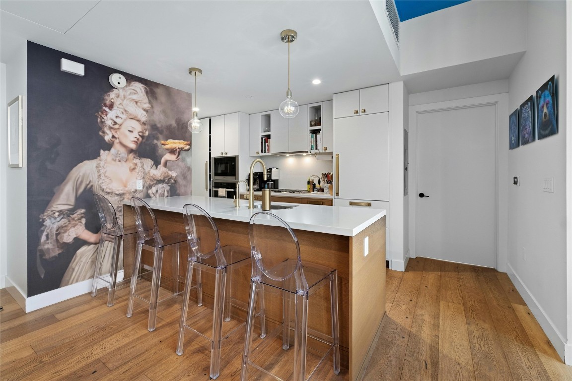70 Rainey Street, Unit 2702 Austin, TX 78701 - Photo 7 of 40 a kitchen with stainless steel appliances granite countertop a sink a stove a refrigerator and island with wooden floor