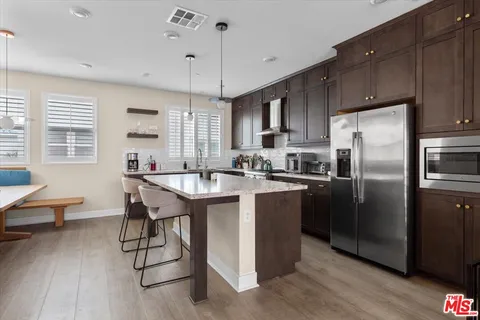 a kitchen with stainless steel appliances granite countertop a stove a sink a refrigerator a center island and a counter space