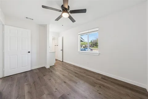 an empty room with wooden floor ceiling fan and windows