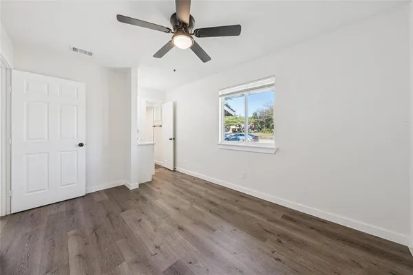 an empty room with wooden floor ceiling fan and windows