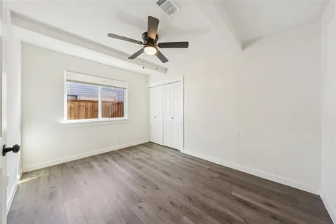 a view of a big room with wooden floor ceiling fan and windows