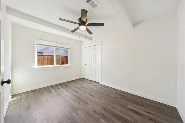 a view of a big room with wooden floor ceiling fan and windows