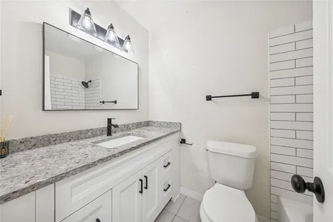 a bathroom with a granite countertop toilet sink and mirror