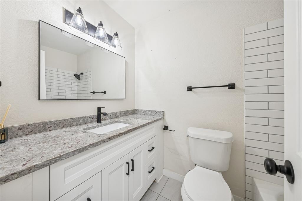 2126 Travis Drive Carrollton, TX 75006 - Photo 20 of 23 a bathroom with a granite countertop toilet sink and mirror
