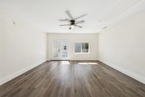 an empty room with wooden floor ceiling fan and windows