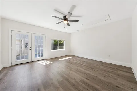 an empty room with wooden floor chandelier fan and windows