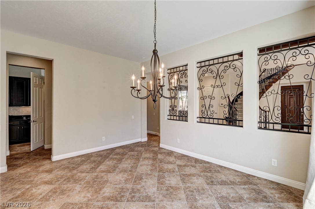 2793 Rosenhearty Drive Henderson, NV 89044 - Photo 27 of 85 This formal dining room features tiled floors, an elegant chandelier, and decorative wrought iron accents overlooking the foyer and staircase.