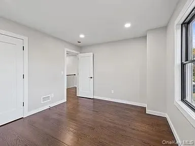 a view of an empty room with wooden floor and window