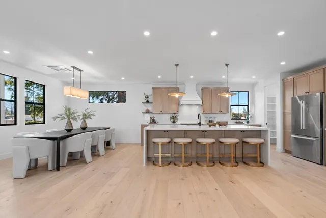 a kitchen with stainless steel appliances kitchen island granite countertop a table chairs sink and microwave