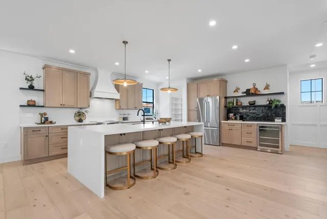 a kitchen with stainless steel appliances granite countertop a sink a stove a dining table and chairs