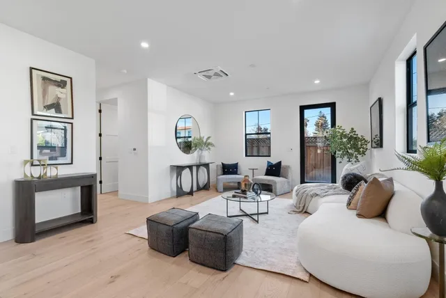 a kitchen with kitchen island granite countertop a stove a sink a dining table and chairs with wooden floor