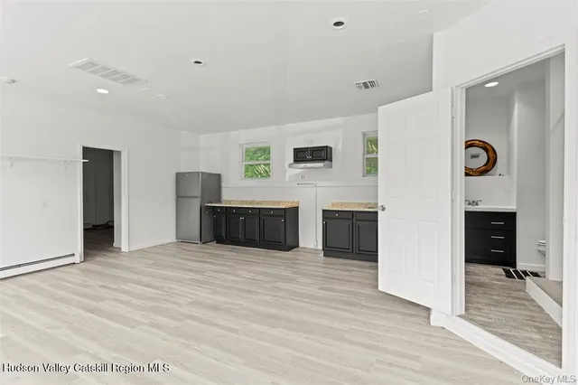 a spacious bedroom with a bed and a view of kitchen