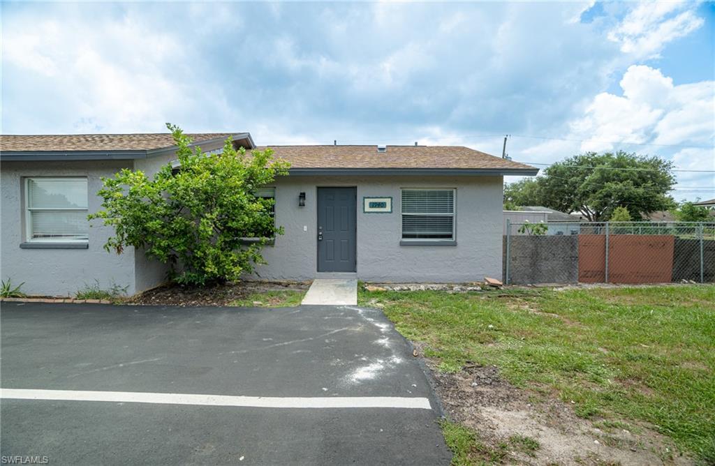 1940 48th Street Southwest Naples, FL 34116 - Photo 2 of 33 Exterior featuring a gray stucco finish, brown shingle roof, and a dark gray entry door