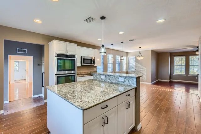 a kitchen with granite countertop kitchen island a sink appliances and wooden floor