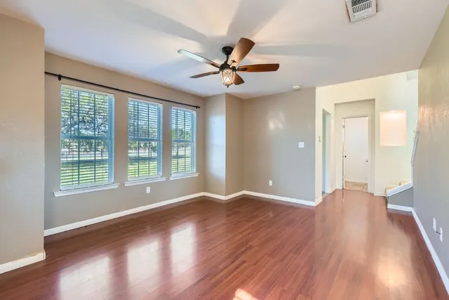 a view of an empty room with window and wooden floor