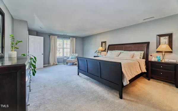 a bedroom with a bed table flowerpot and window