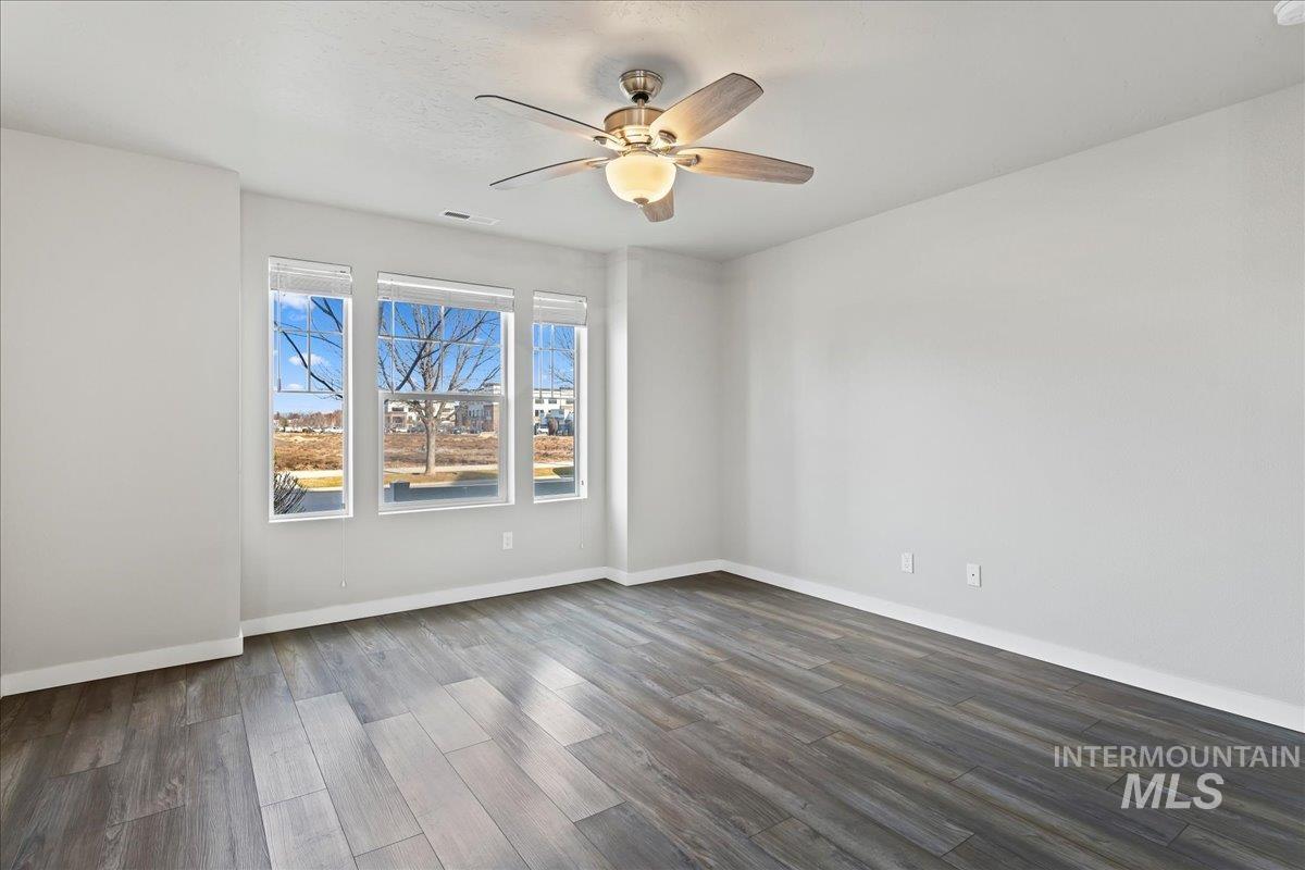 2471 East Goldstone Street Meridian, ID 83642 - Photo 13 of 27 Empty room featuring dark wood-type flooring and a ceiling fan