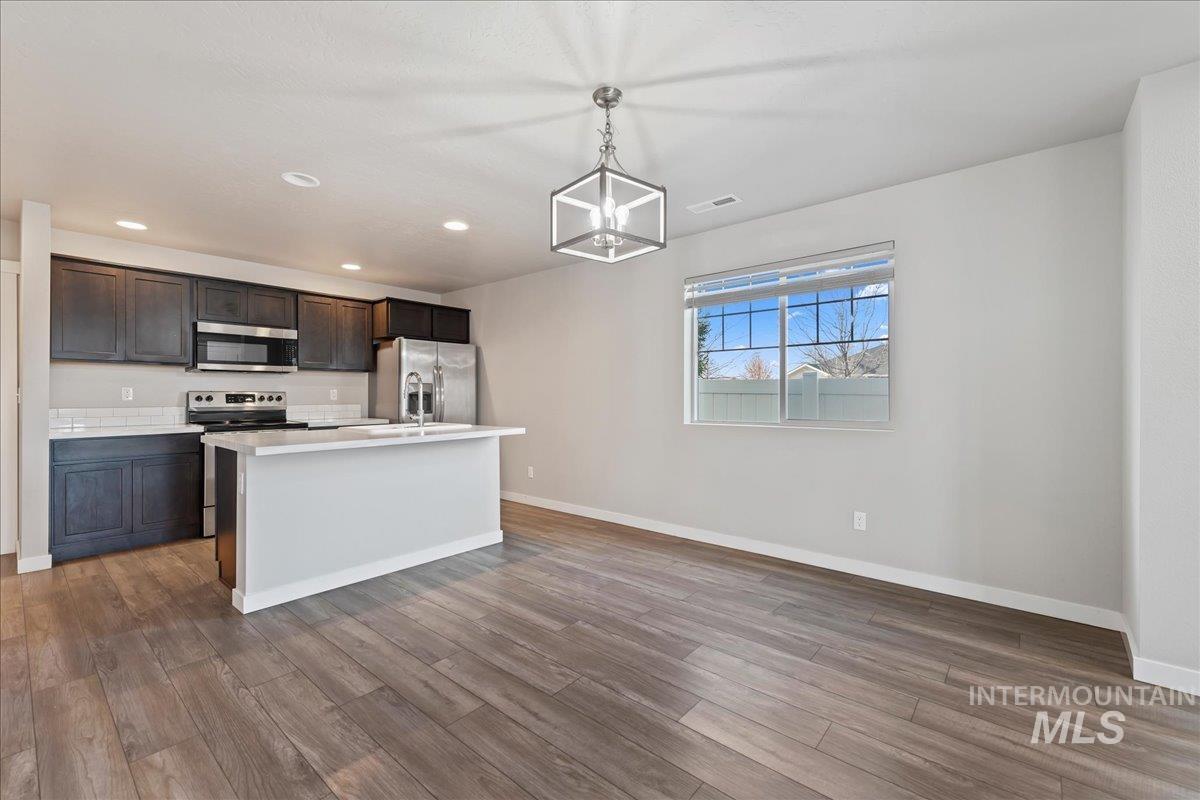2471 East Goldstone Street Meridian, ID 83642 - Photo 8 of 27 Kitchen with stainless steel appliances, light countertops, pendant lighting, a kitchen island with sink, and light wood finished floors