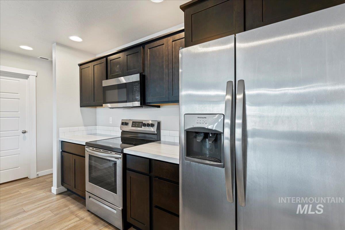2471 East Goldstone Street Meridian, ID 83642 - Photo 10 of 27 Kitchen with stainless steel appliances, light countertops, dark brown cabinets, recessed lighting, and light wood finished floors