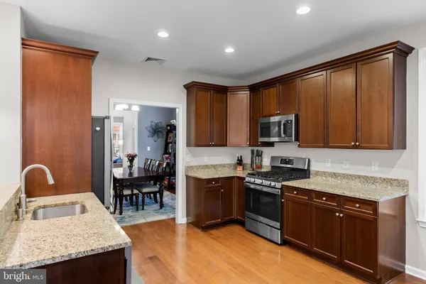 a kitchen with stainless steel appliances granite countertop wooden cabinets a stove top oven a sink and dishwasher