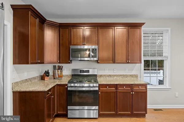 a kitchen with stainless steel appliances granite countertop a stove a sink and a microwave