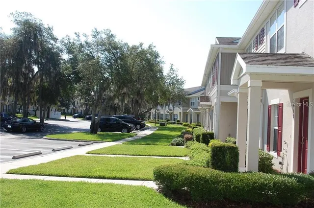 a view of a house with a big yard potted plants and large tree