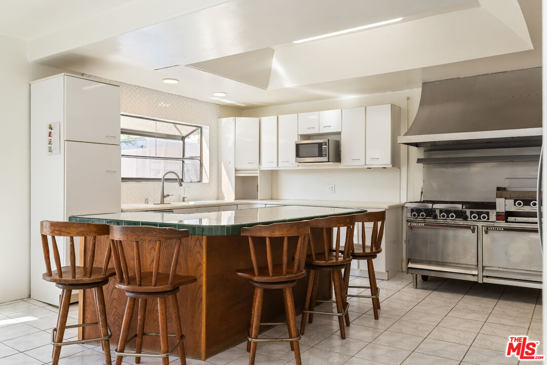 955 South Highland Avenue Los Angeles, CA 90036 - Photo 16 of 47 a kitchen with granite countertop a table chairs stove and cabinets