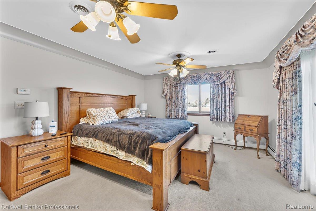 7410 Wilson Road Montrose, MI 48457 - Photo 24 of 38 Bedroom featuring light carpet, a ceiling fan, and a baseboard heating unit