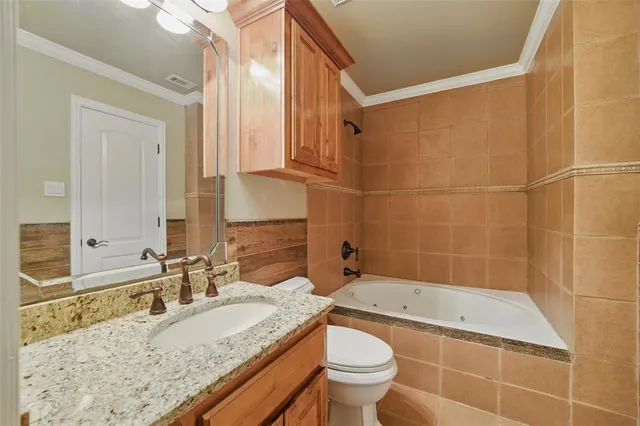 a bathroom with a granite countertop bathtub sink vanity mirror and toilet