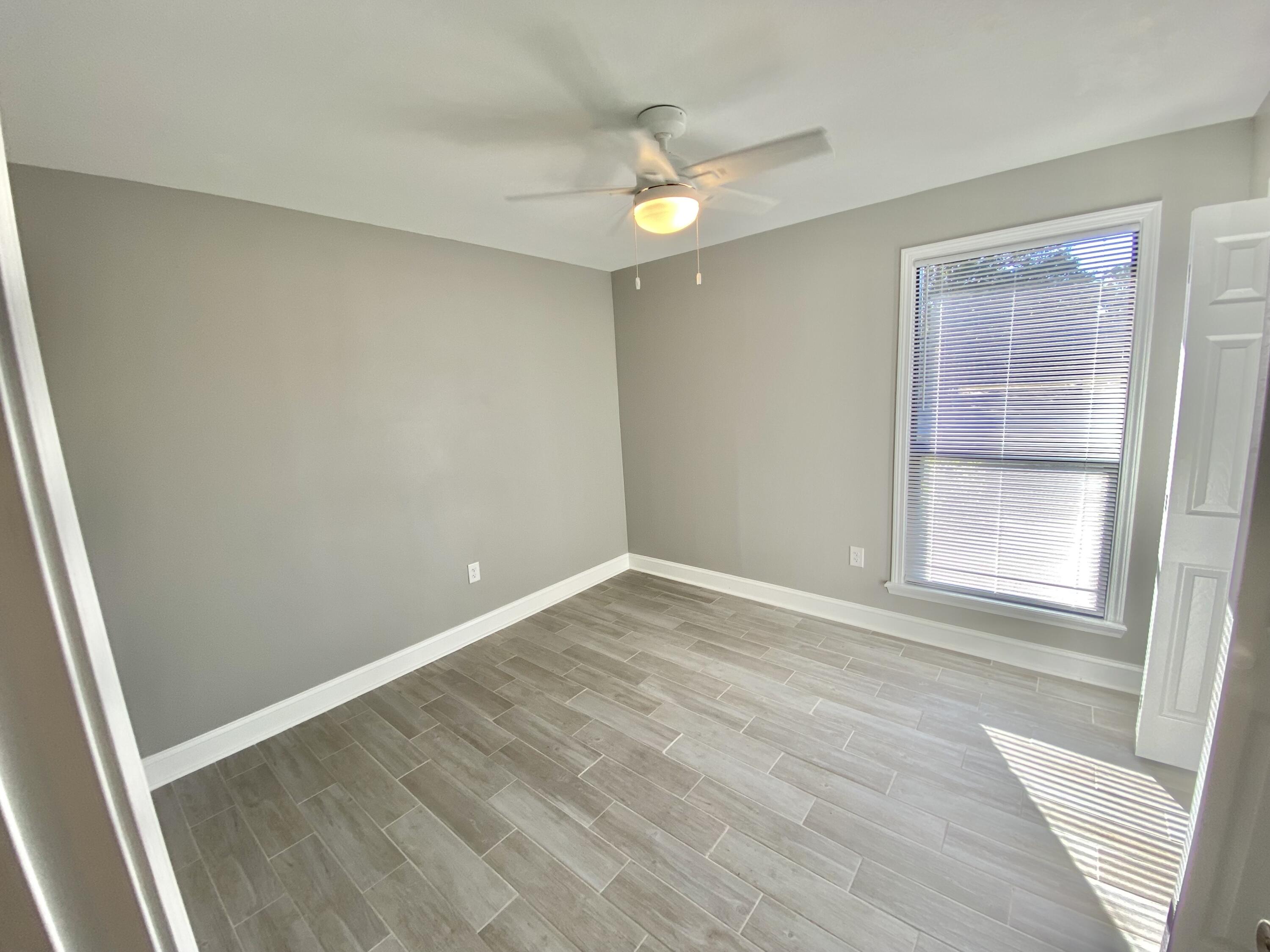 795 Bay Street Crestview, FL 32536 - Photo 17 of 34 a view of an empty room with wooden floor and a window