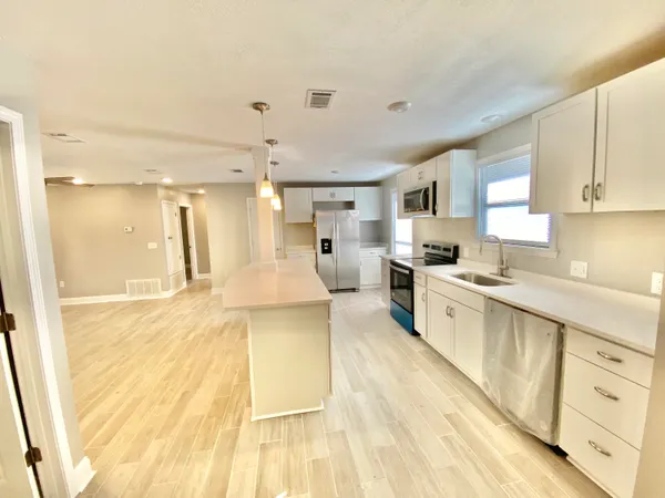 a large kitchen with cabinets a sink and a stove top oven