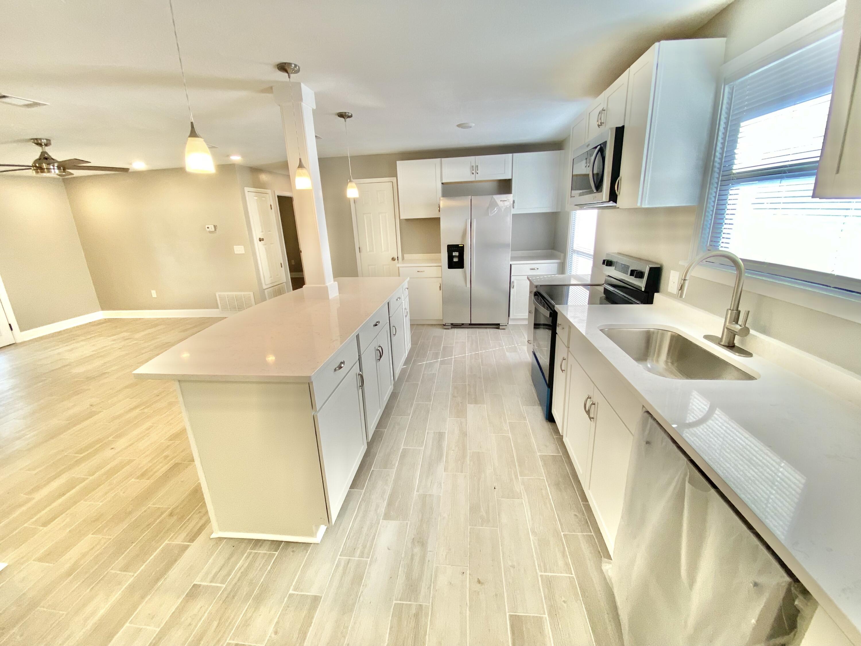 795 Bay Street Crestview, FL 32536 - Photo 9 of 34 a large white kitchen with wooden floor