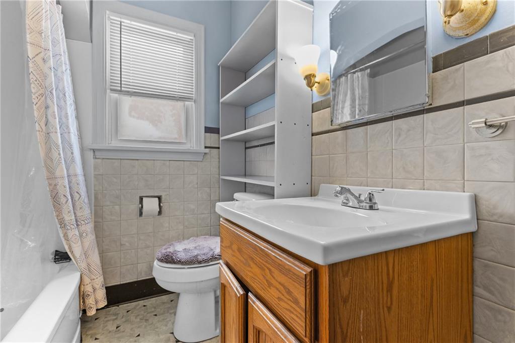 118 Oak Spring Road Canonsburg, PA 15317 - Photo 13 of 32 Full bathroom with tiled walls, wood vanity, and built-in shelving for storage. A shower/tub combo and natural light from the window make it practical and inviting.