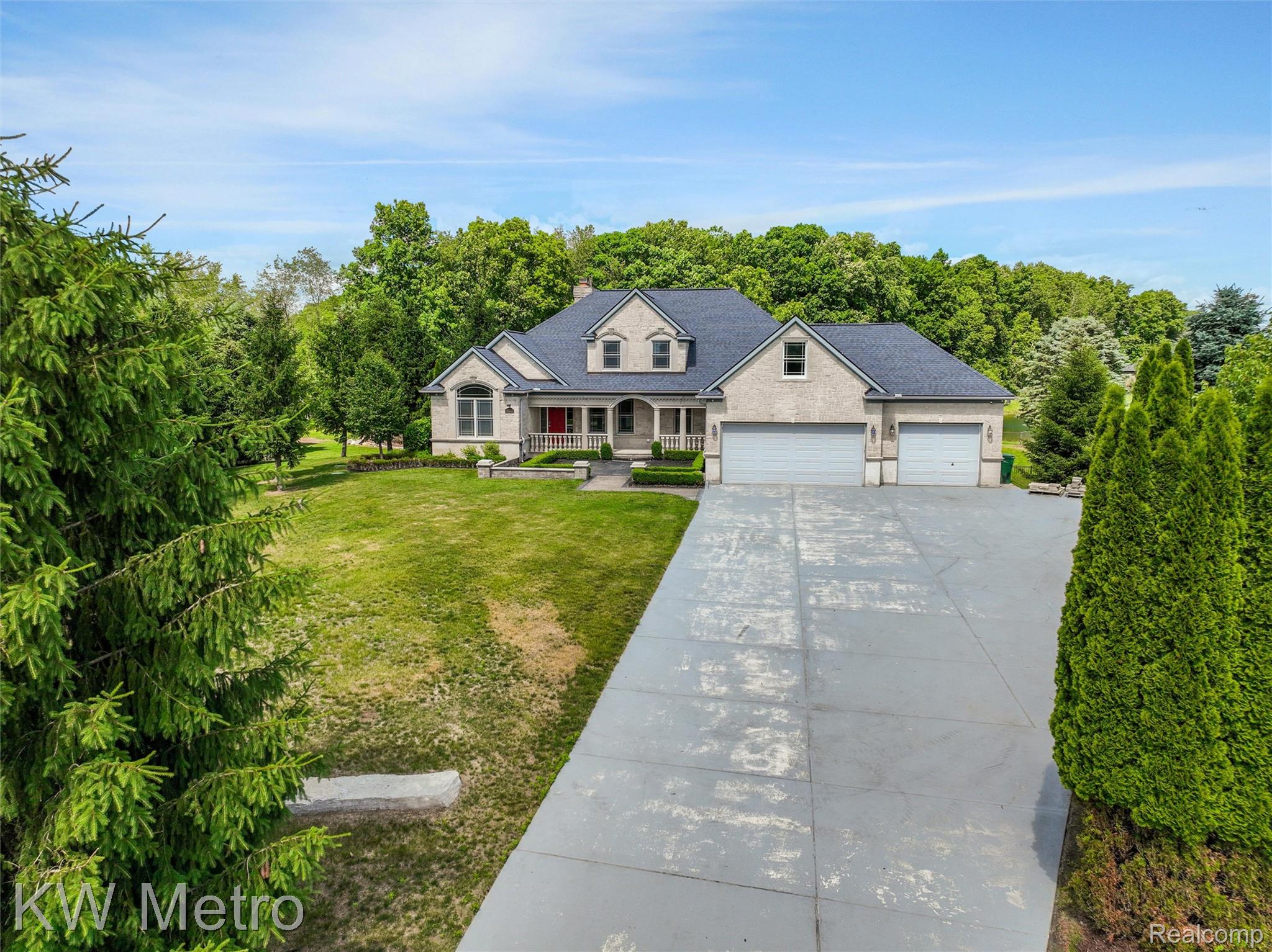 65884 Windrose Court Ray, MI 48096 - Photo 6 of 82 Spacious residence featuring a light-colored brick exterior, dark shingle roof, and a prominent front porch with white columns