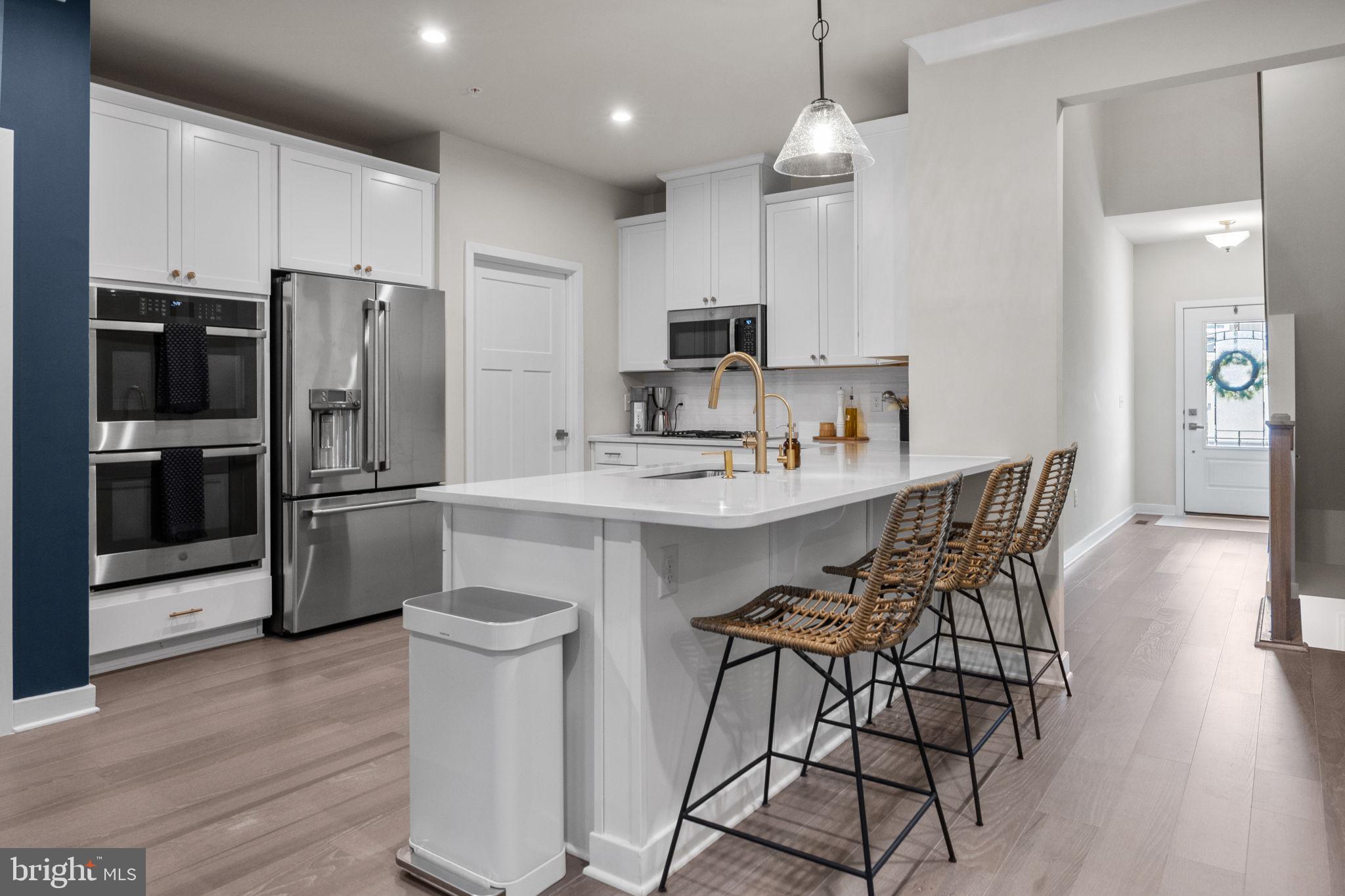 a kitchen with stainless steel appliances kitchen island granite countertop a refrigerator a sink dishwasher a stove and a oven with wooden floor