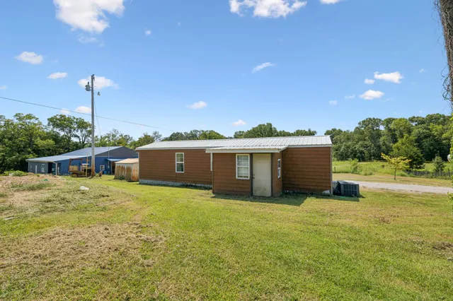 a view of a patio with table and chairs under an umbrella with a small yard