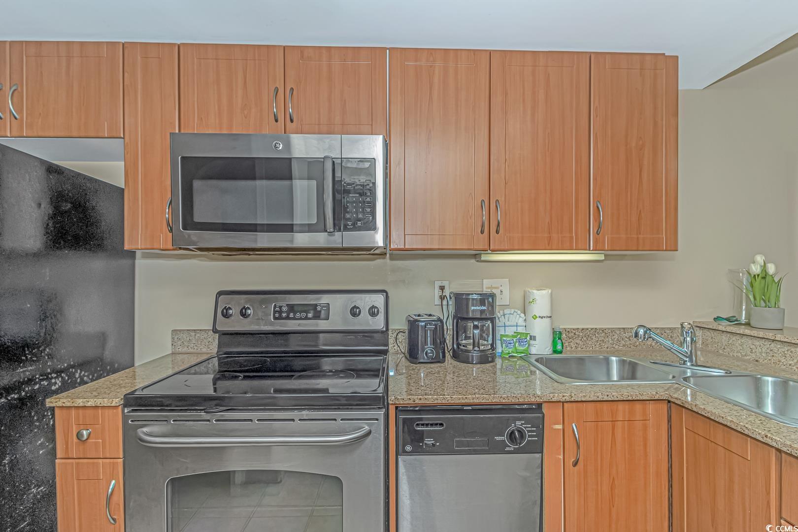 201 South Ocean Boulevard, Unit 1610 Myrtle Beach, SC 29577 - Photo 12 of 40 Kitchen with stainless steel appliances, light stone counters, and brown cabinetry