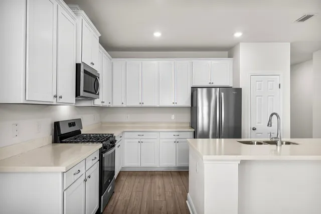 a kitchen with white cabinets sink and stainless steel appliances