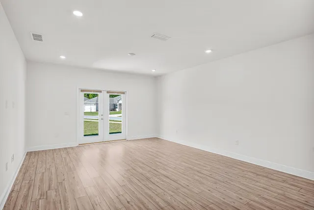 a view of an empty room with wooden floor and closet
