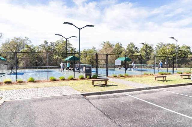 a view of swimming pool with lawn chairs and large trees