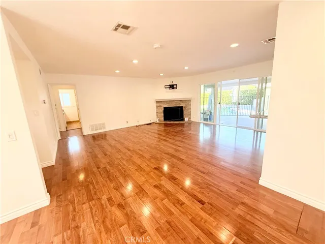 a view of empty room with wooden floor and fireplace