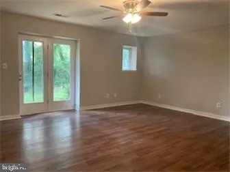 an empty room with wooden floor fan and windows